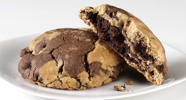 A pair of peanut butter chocolate cookies on a plate revealing chocolate and peanut butter layers.