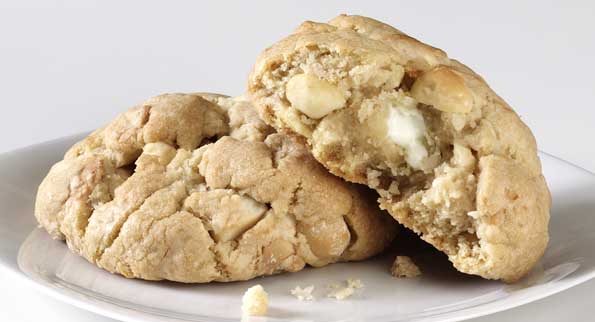 Gooey white chocolate macadamia cookies temptingly split to unveil rich chunks, ready for a treat.