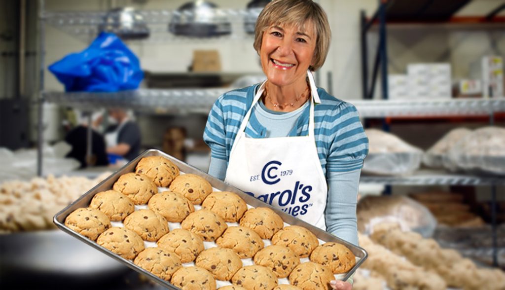 Famous cookie baker Carol presenting a tray of handmade gourmet cookies in her bakery.